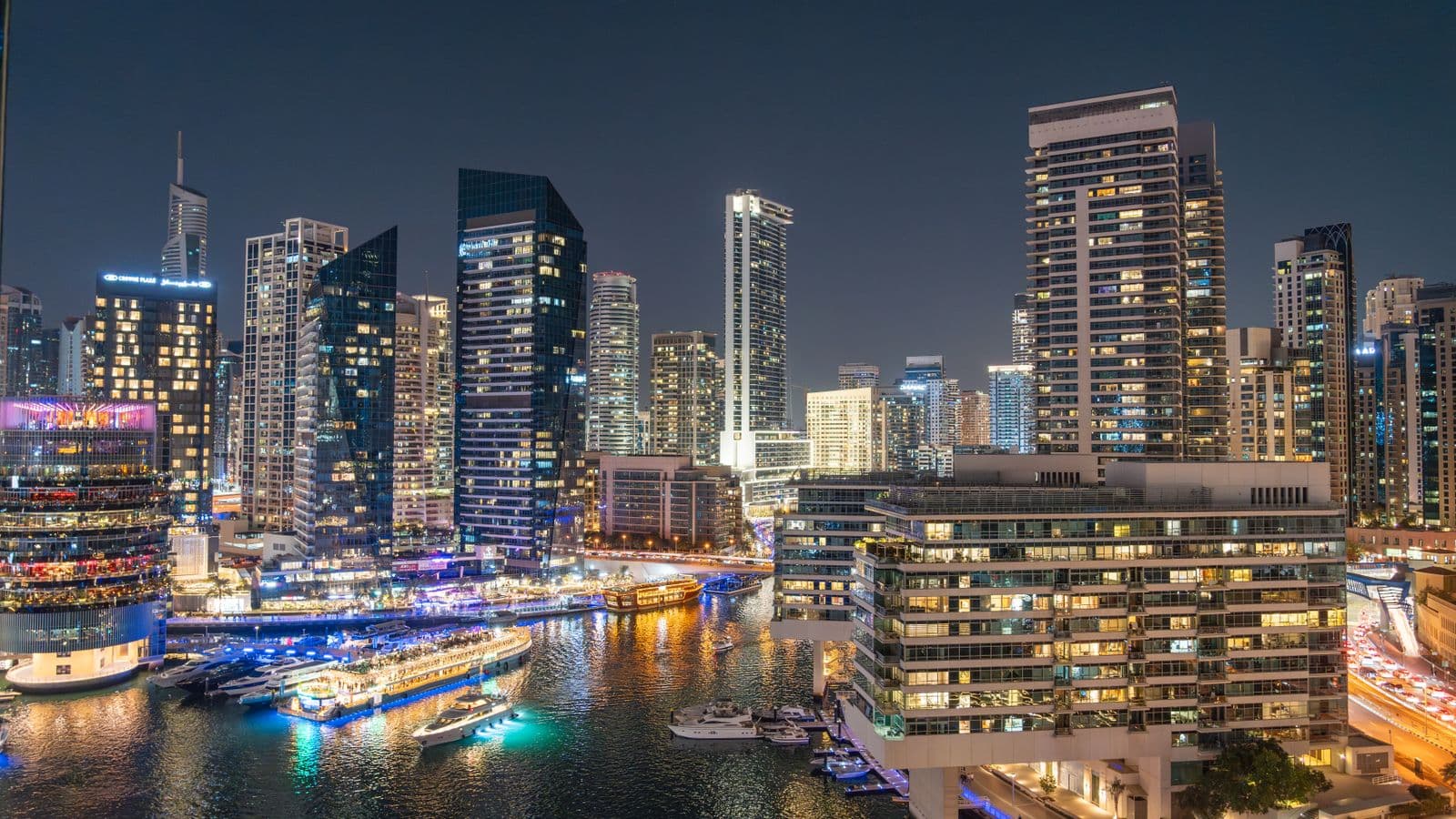 Dubai Marina towers lit up at night above the waterfront promenade