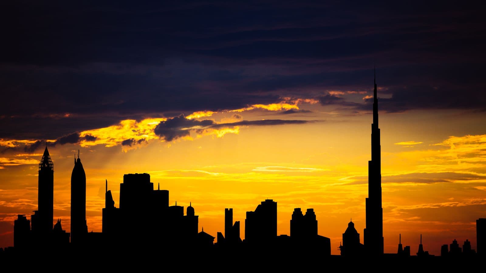 Dubai skyline silhouetted against an amber sunset